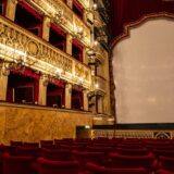A theater with red seats and a large screen